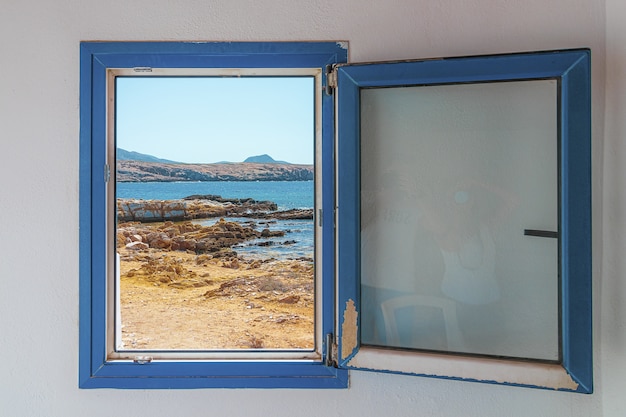 Ventana azul de madera vieja con la vista de la playa