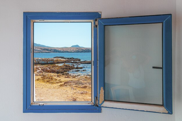 Ventana azul de madera vieja con la vista de la playa