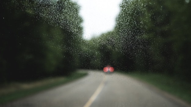 Ventana de cristal con una vista borrosa de un coche en una carretera
