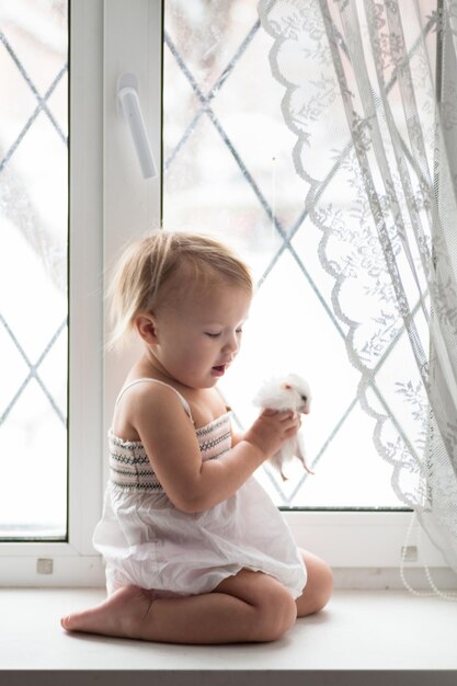 Ventana de niña pequeña con hámster estilo de vida interior real niños y mascotas