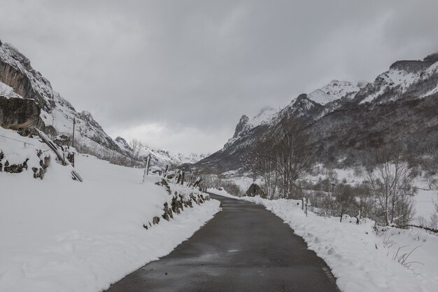 Ver una carretera estrecha con altas montañas cubiertas de nieve a ambos lados