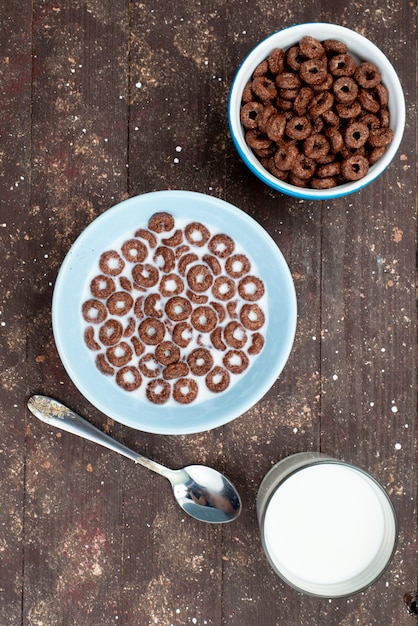 Para ver distante, vea los cereales de chocolate con leche dentro de un plato azul y junto con una cuchara de café, alimentos para el desayuno de cereales.