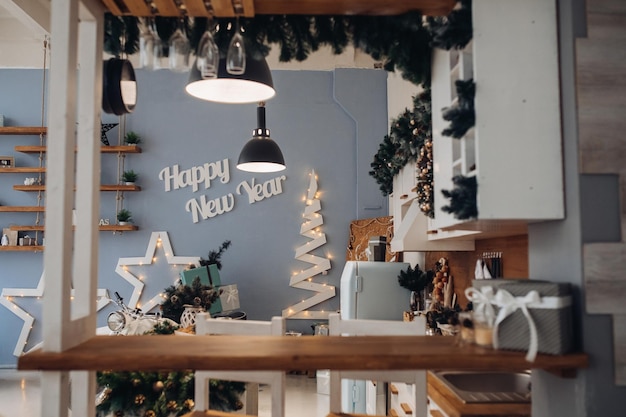 Ver más cocina moderna decorada para Navidad con estrellas decorativas, objetos y árbol de Navidad decorativo con regalos de Navidad.