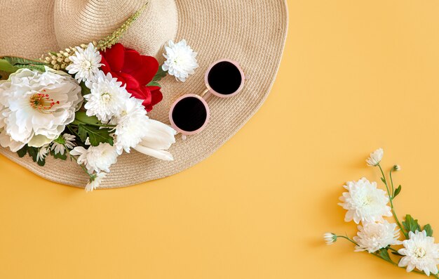 Verano con flores blancas y un sombrero de mimbre con gafas de sol