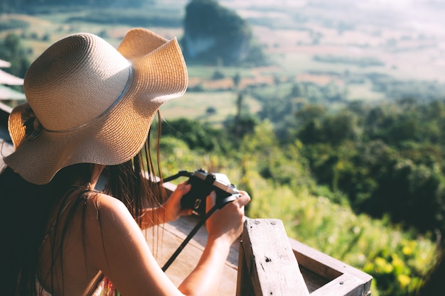 Verano hermosa chica sosteniendo una cámara con vista a la montaña