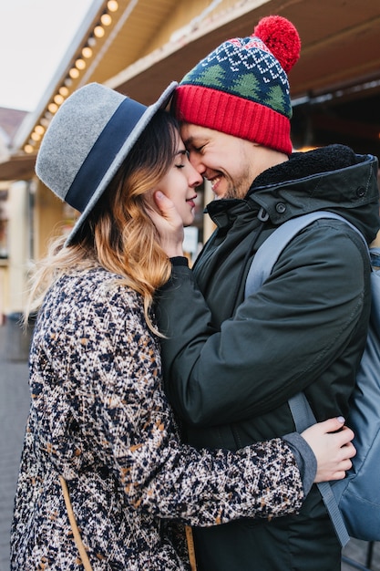 Verdaderas emociones de amor de linda pareja alegre disfrutando de tiempo juntos al aire libre en la ciudad. Encantadores momentos felices, divertirse, sonreír, Navidad, citas, enamorarse.