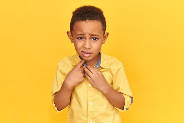 Verdaderas reacciones, emociones y sentimientos humanos. Niño preescolar asustado emocional en chaqueta con mirada asustada, señalando con el dedo índice a sí mismo