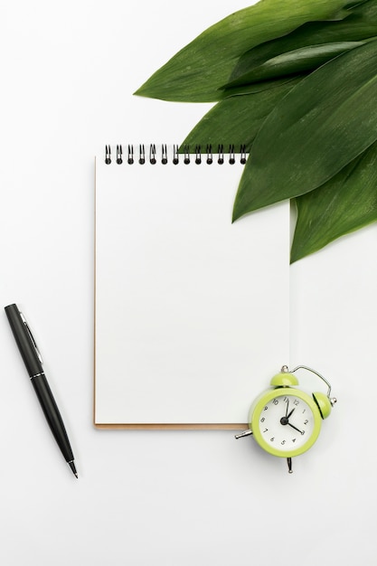 Foto gratuita el verde se va en la libreta espiral con el reloj de alarma y la pluma en el contexto blanco