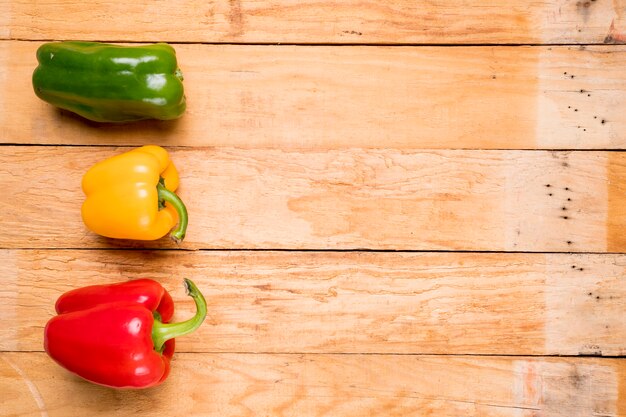 Verde; Pimientos rojos y amarillos en tablón de madera