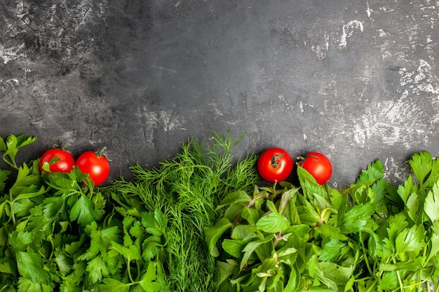 Verdes y tomates de vista superior en superficie oscura