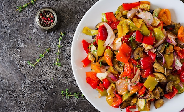 Verduras al horno en un plato blanco. Berenjenas, calabacines, tomates, pimentón y cebolla. Vista superior