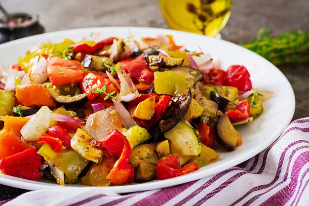 Verduras al horno en un plato blanco. Berenjenas, calabacines, tomates, pimentón y cebolla.