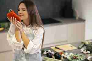 Foto gratuita verduras. bastante joven oliendo un pimiento rojo con los ojos cerrados