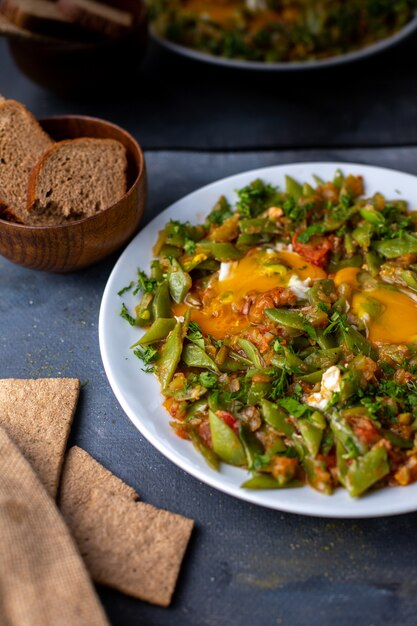 verduras cocidas coloridas diferentes junto con pan en el escritorio gris