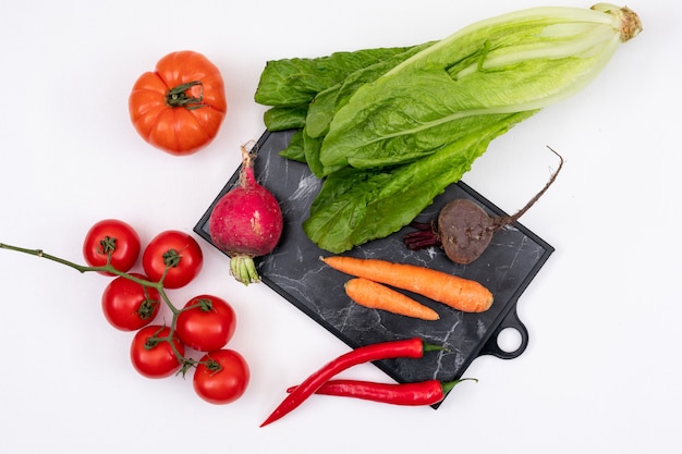 verduras coloridas en tabla de cortar de madera en blanco