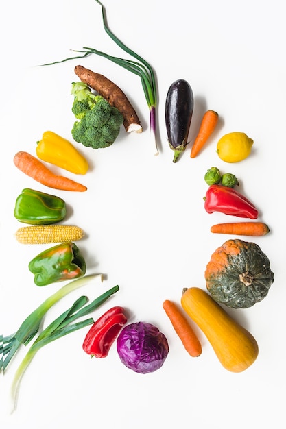 Verduras crudas coloridas que forman el marco en la superficie blanca