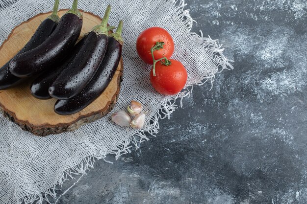 Verduras crudas frescas. Berenjenas moradas sobre tablero de madera y tomate.