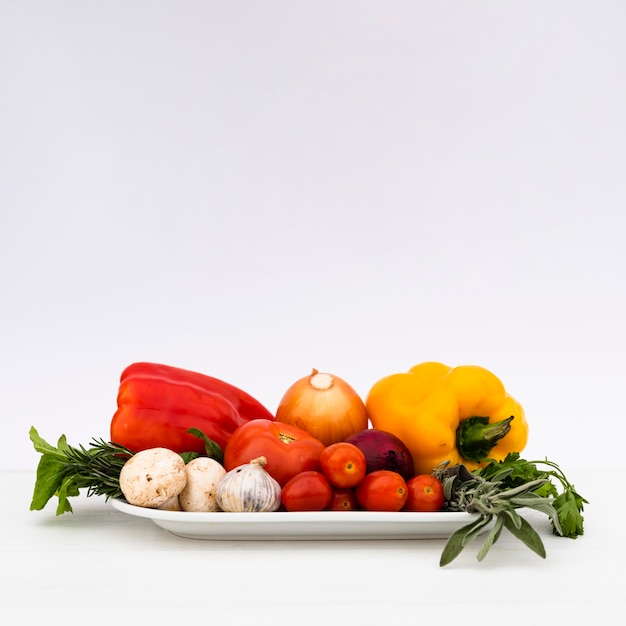 Verduras crudas sanas frescas en bandeja en el fondo blanco