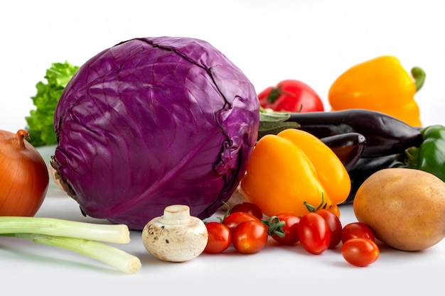 Verduras frescas de colores maduros sobre fondo blanco.