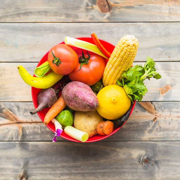 Verduras frescas de colores en un tazón sobre tablero de madera