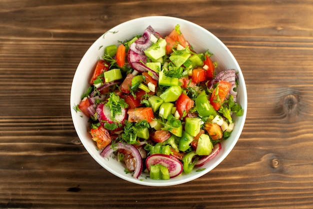 Verduras frescas coloridas en rodajas como pepinos tomates rojos cebolla en la superficie rústica de madera