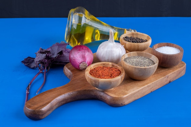 Verduras frescas, especias y botella de aceite de oliva sobre tabla de madera