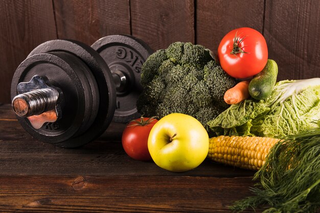 Verduras frescas y pesas sobre fondo de madera