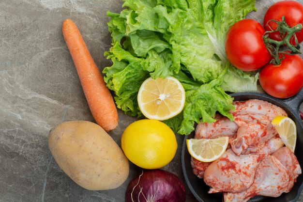 Verduras frescas con pollo crudo sobre fondo de mármol. Foto de alta calidad