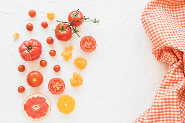 Verduras frescas y servilleta a cuadros del patrón en el contexto blanco