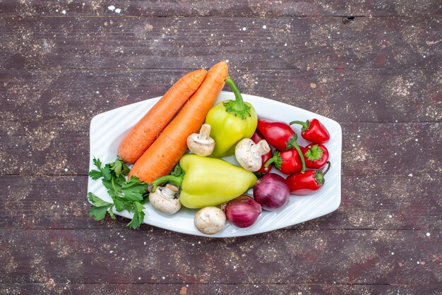 Verduras frescas con setas dentro de la placa en el escritorio marrón, comida vegetal seta