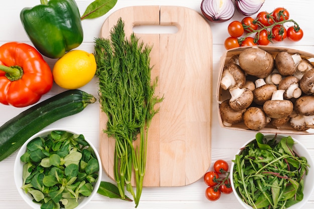 Foto gratuita verduras frescas con tabla de cortar de madera.