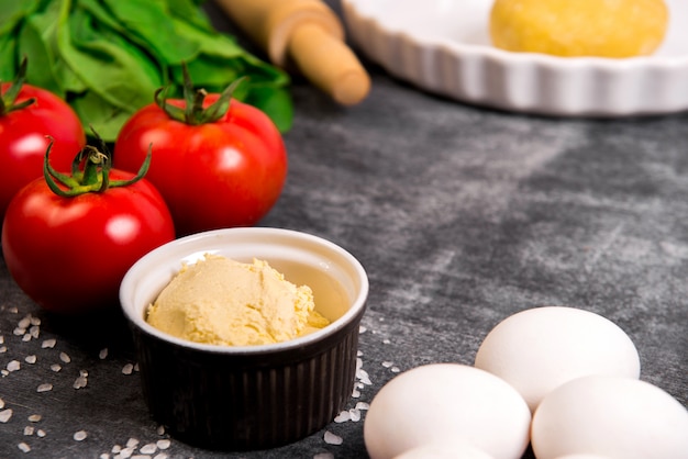 Foto gratuita verduras y masa sobre superficie de madera gris