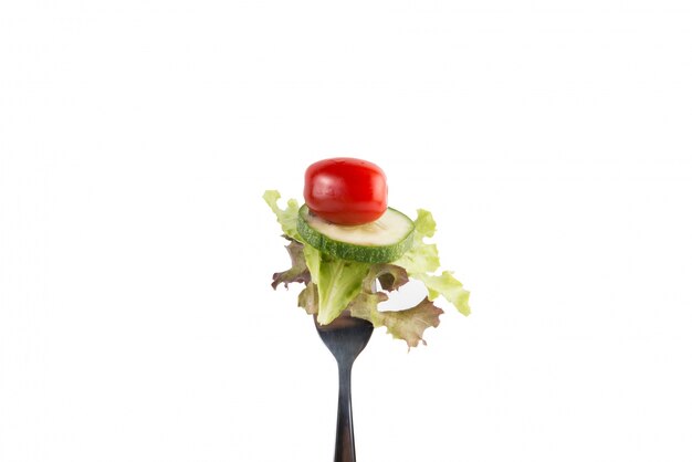 Verduras mixtas frescas en un tenedor aisladas sobre fondo blanco.