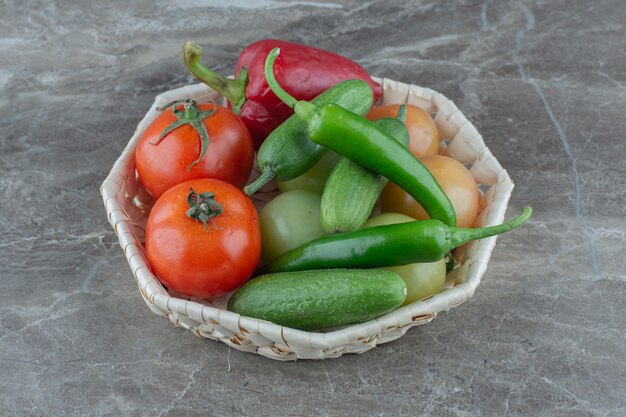 Verduras orgánicas frescas en canasta sobre superficie gris