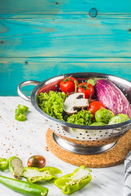 Foto gratuita verduras orgánicas frescas en colador sobre mesa de mármol