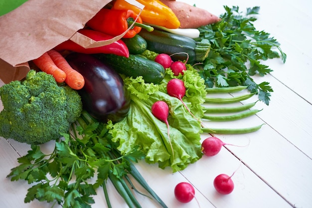 Verduras orgánicas frescas sobre fondo de tablas de madera blancas, vista superior. Concepto de comida saludable.