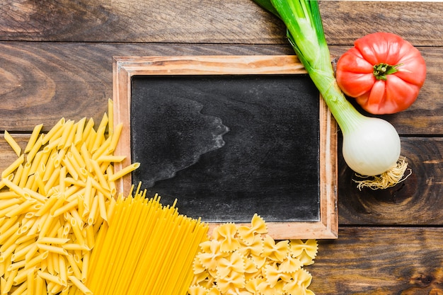 Foto gratuita verduras y pasta cerca de pizarra