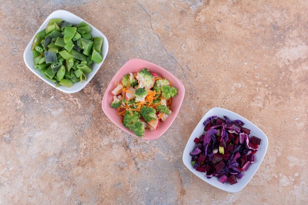 Verduras picadas mezcladas y agrupadas en tazones sobre una toalla sobre una superficie de mármol