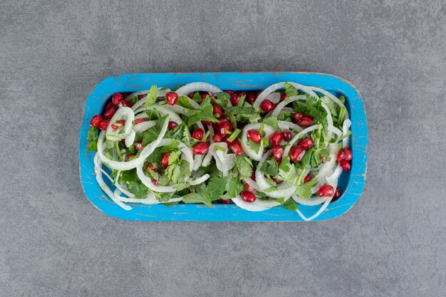 Verduras en rodajas, cebollas y semillas de granada en placa azul. Foto de alta calidad