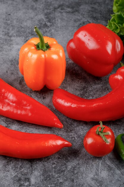 Verduras rojas y amarillas sobre la mesa gris.