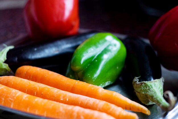 Verduras verduras maduras frescas como zanahorias anaranjadas berenjenas negras y pimiento verde