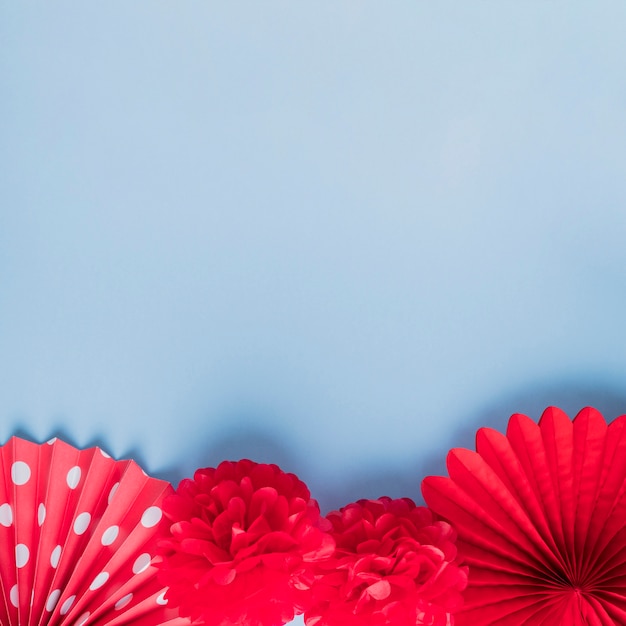 Foto gratuita veridad de flores de origami falso rojo sobre superficie azul