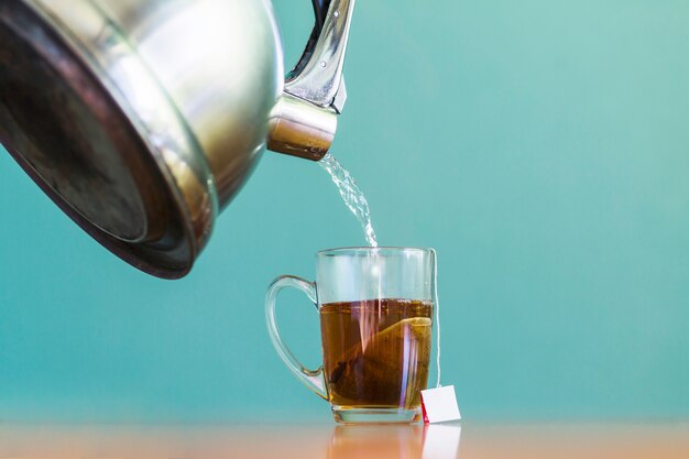 Verter agua en una taza de té de vidrio