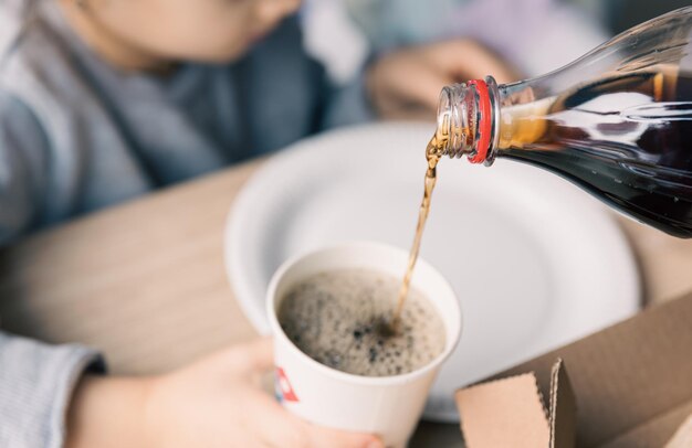 Verter la bebida gaseosa de la botella al vaso de cerca