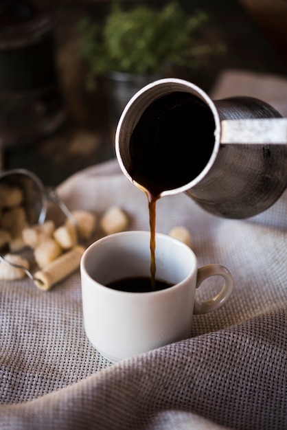 Verter café de una tetera en una taza