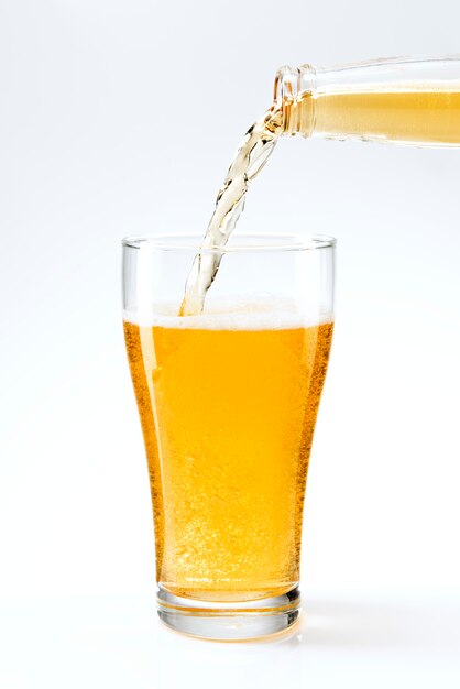 Verter la cerveza en un vaso de una botella de cerveza