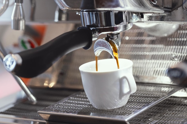 Verter espresso en la taza de la máquina