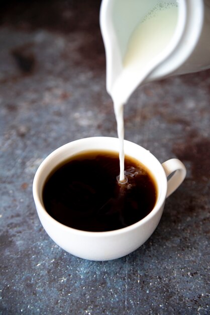 Verter la leche fresca en una taza de café