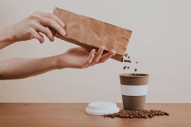 Verter a mano los granos de café de una bolsa de papel en una taza de café