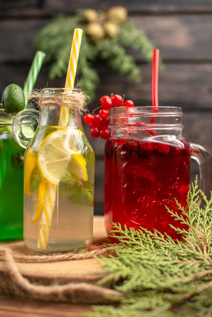 Vertical de jugos orgánicos fuit en botellas servidas con tubos sobre una tabla de cortar de madera sobre una mesa marrón